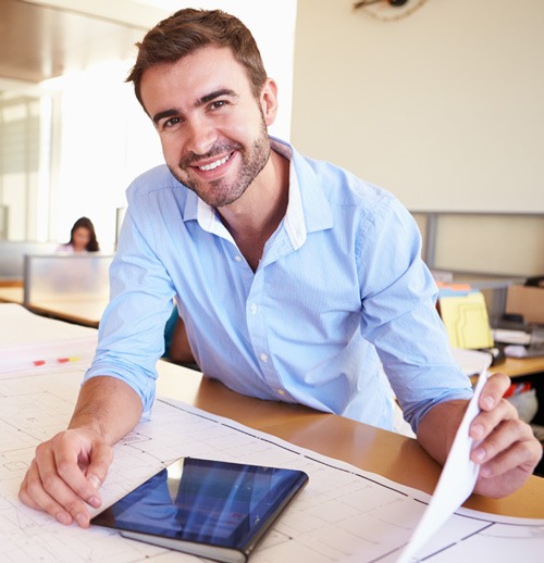 Architect sitting on his desk and looking at the camera