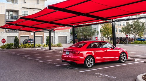 red shade structure covering a parking lot where a red audi is parked