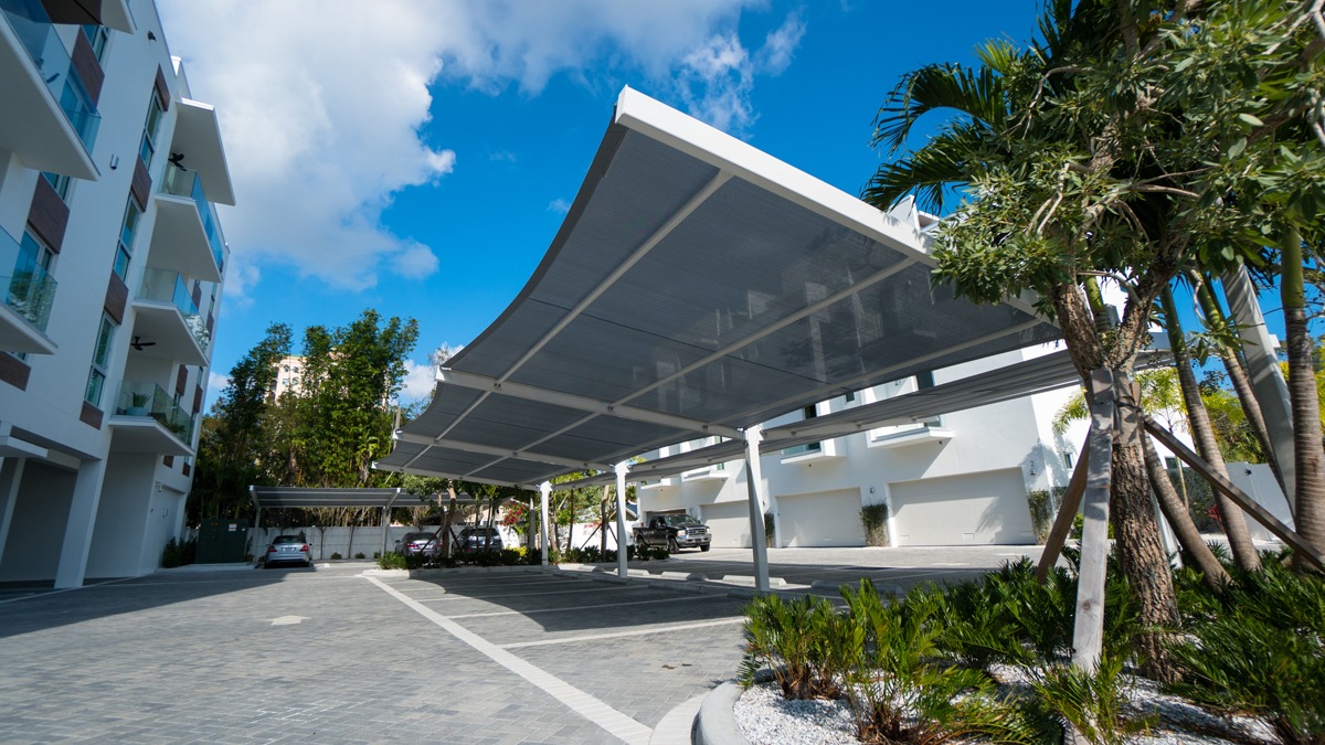 Square shade structure over parking lot row outside apartment complex.